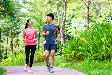 Asiatischer chinesischer Mann und Frau, die im Stadtpark joggen