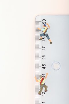 scalatori in miniatura in arrampicata su un righello in centimetri