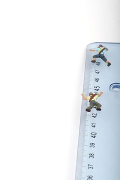 scalatori in miniatura in arrampicata su un righello in centimetri
