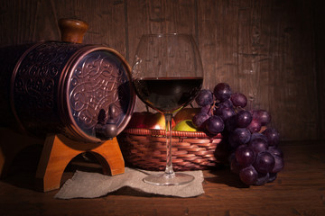 Glass of red wine and barrel on rustic wood tabel