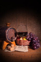 Obraz na płótnie Canvas Glass of red wine and barrel on rustic wood tabel