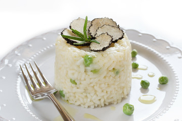 Italian risotto with black truffle and green peas on white plate