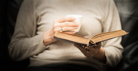 Woman reading an old book while drinking a coffee - Donna che legge un vecchio libro mentre...