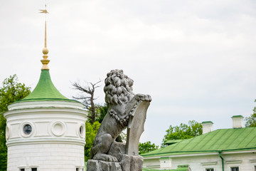 Obraz premium Statue of lion holding a shield in its paws. Regal lion leaning on empty heraldic shield near the castle entrance. The palace and park complex Manor Tarnowski, s.Kachanovka, Ukraine.