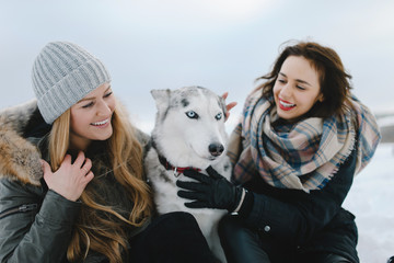 Two adorable girls posing with their husky dog on winter vacation day in park © sergiubirca