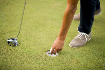 Golf ball, putter and boy's legs on green
