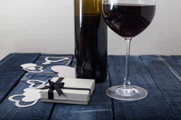 glass of red wine and gift on denim background