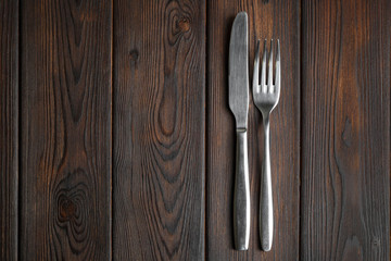 Fork and knife on dark wood background