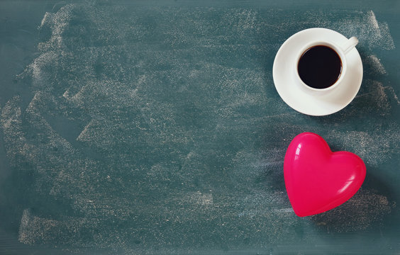 top view image of pink heart and cup of coffee on blackboard background. valentine's day celebration concept
