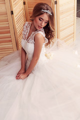 Naklejka na ściany i meble gorgeous young bride with blond curly hair, wears elegant wedding dress and crown