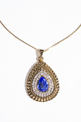 gold pendant with blue gem on a white background