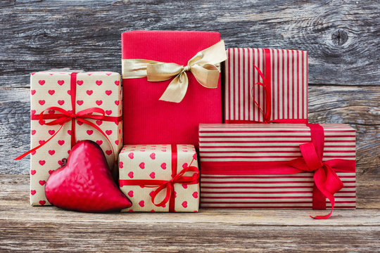 Wrapped gifts and red heart on wooden background. Toned, soft focus, vintage style 