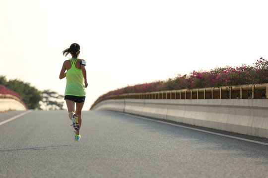 young woman runner running on city bridge road