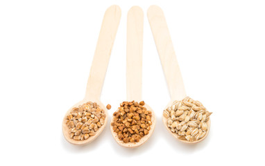 barley, wheat, buckwheat, oat groats in a wooden spoon isolated