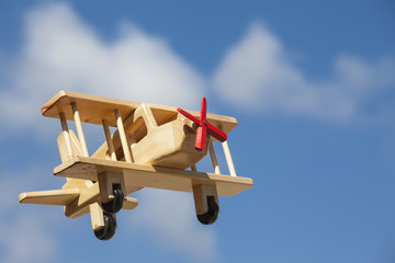 Avión de madera volando con cielo azul y nubes blancas - Elevándose