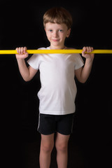 Boy athlete performs exercises with gymnastic stick in the gym