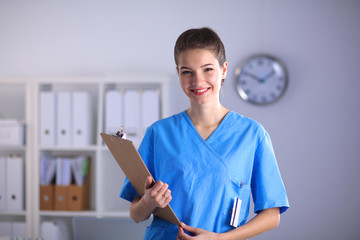 Smiling female doctor with a folder in uniform standing at hospital - 99721191