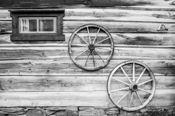 Fototapeta na wymiar Facade of a wooden cabin with small window and two wooden wagon