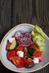 Salad with tomatoes, feta cheese, olives, lettuce into a bowl