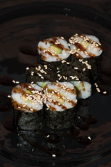 Sushi rolls lie on a black background