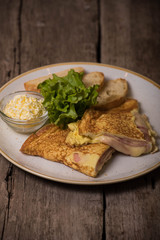 An omelet with ham and melted cheese, slices of white bread, grated butter on a plate