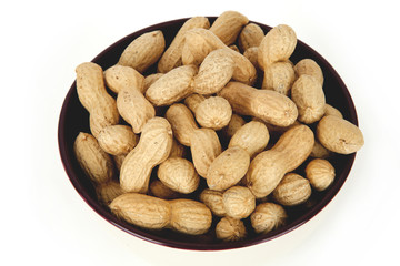 peanuts on a white background with shell in a ceramic bowl