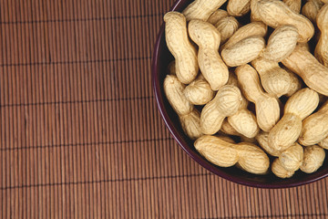 peanuts on a brown background in a ceramic bowl