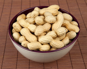 peanuts on a brown background in a ceramic bowl