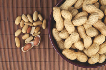 peanuts on a brown background in a ceramic bowl