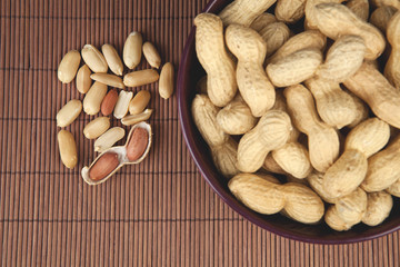 peanuts on a brown background in a ceramic bowl