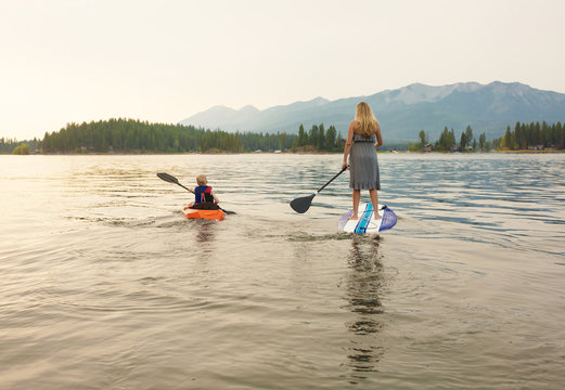 Paddle boarding on scenic mountain lake at dusk 