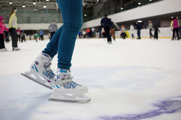 Feet skater in motion on the ice rink with many people. Figure skates - obrazy, fototapety, plakaty