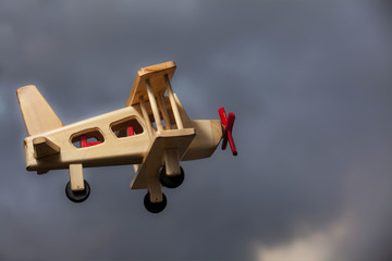Avión de madera volando bajo el cielo tormentoso - Vista lateral