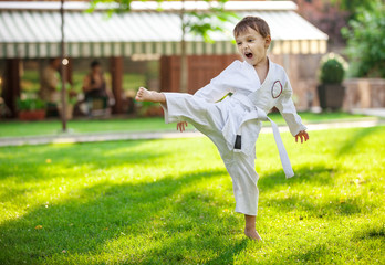 Preschool boy practicing karate outdoors 