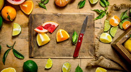 Sliced citrus fruits - grapefruit, orange, tangerine, lemon, lime on the old Board with box.