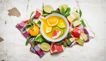 The juice from citrus fruits - grapefruit, orange, tangerine, lemon, lime in a cup with leaves.