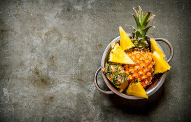 Fresh pineapples in the pan. On stone table.