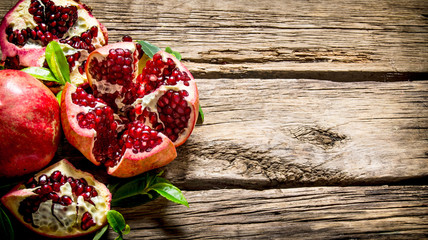 Fresh red pomegranate with leaves. On wooden background.