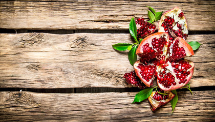 Fresh red pomegranate with leaves. On wooden background.