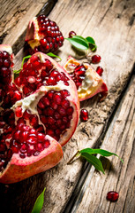 Fresh pomegranate with leaves . On wooden background.