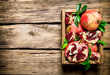 Fresh pomegranates in an old box with leaves.