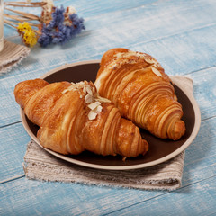 Two croissant with almonds on blue wooden surface
