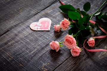 Beautiful pink roses on a dark wooden table with a pink ribbon