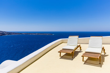 Beach chairs on the terrace at the beach, blue sky, sea and sun in Greece