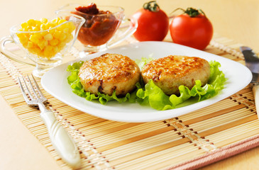 Two chicken cutlets on the green leaf lettuce.