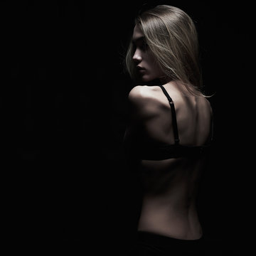 young woman with naked back over black background.sexy body girl