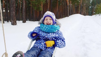 The little girl laughs and goes on a sled