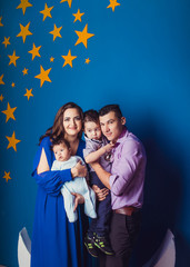 A young family of four on blue background in children's room