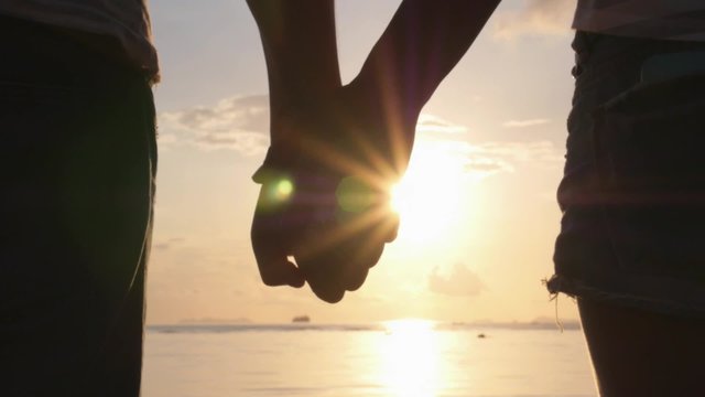 Romantic Couple Holding Hands on Beach at Sunset. 