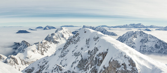 Gorgeous panorama from the the top of Mt. Stol (2236 m) in the Karavanke Alps. Mountain peaks are in the bright sun while valleys are covered by fog.  - obrazy, fototapety, plakaty